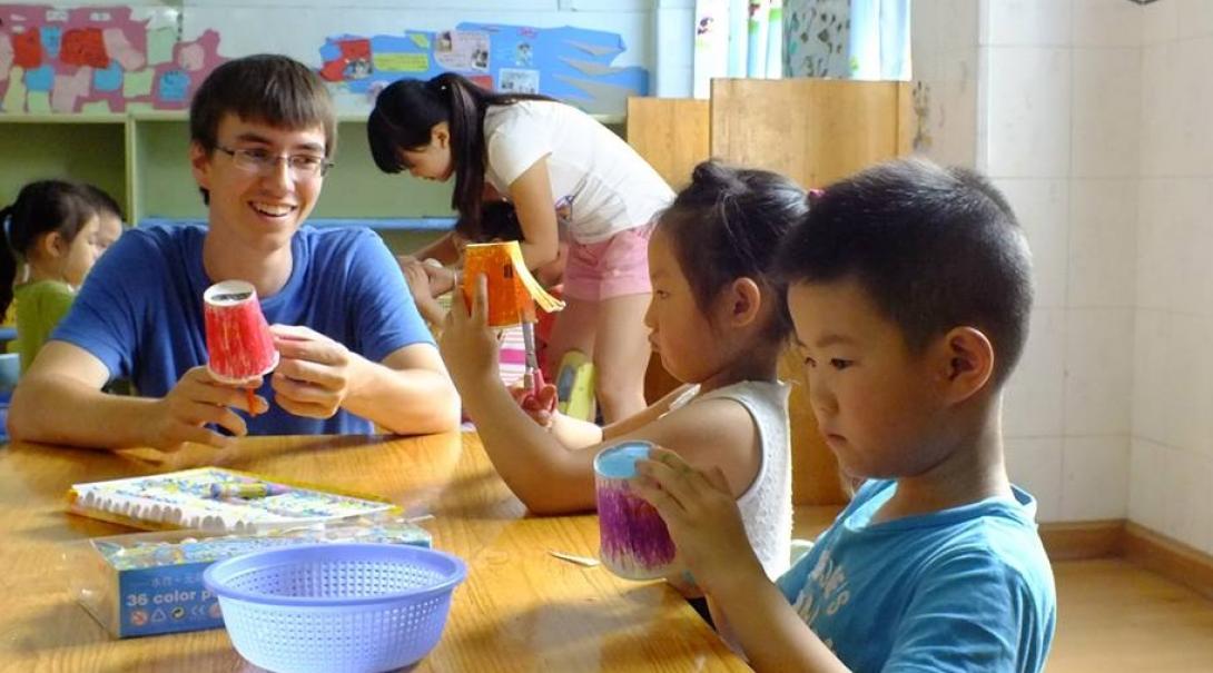 Projects Abroad male volunteer helps with arts and crafts at a day care centre during his Childcare project in China. Projects Abroad volunteers working with children in China participate in an arts and crafts activity at a care centre.